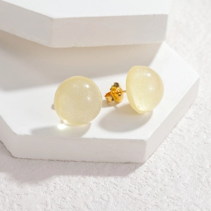 Macro shot of pale yellow resin ball stud earrings with shimmer glitter and gold posts