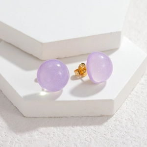Close-up of purple resin ball earrings with glitter on white hexagonal stands