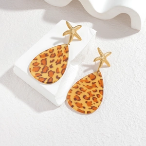 Boucles d'oreilles léopard en forme de goutte et étoile de mer dorée sur fond blanc