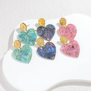 Close-up of three pairs of colorful heart earrings with gold star embossed studs