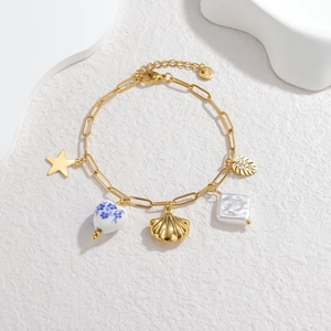 Golden paperclip chain bracelet with ocean charms like shell, leaf and blue floral ceramic heart