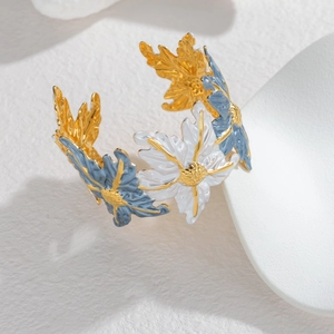 Gold-plated wide open bangle with vintage floral enamel patterns on a white tray