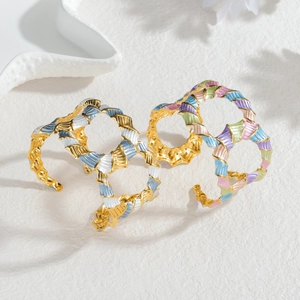 Gold open cuffs with colorful enamel floral textures on white textured background