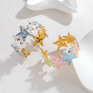 Macro detail of starfish shaped cuff bracelets with colorful enamel and gold accents