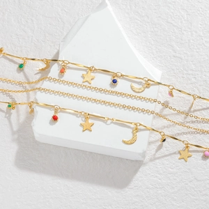 Multilayer gold necklace with star and moon pendants and colorful charms on white stone