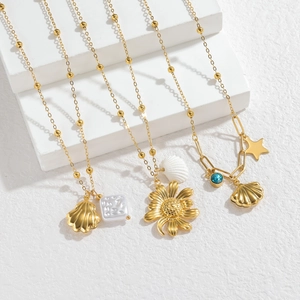 Detailed view of gold chain necklaces with shell and flower pendants on a white block