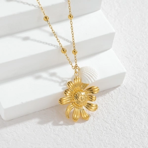 Gold shell sunflower pearl necklace on white stone display with natural shadows