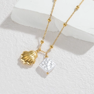 Gold-plated shell and white square pearl pendant necklace on minimalist display