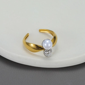 Close-up of matte gold ring featuring a white pearl and silver rhinestone heart detail