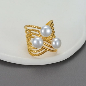Detail of gold multi-layer wrap ring with three white pearls on a white porcelain tray