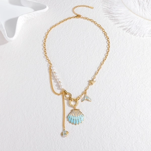 Minimalist stainless steel pearl necklace with shell and fish tail charms on white plate