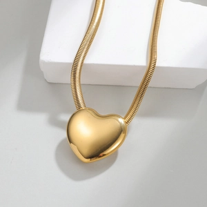 Collier avec pendentif cœur plaqué or 18k et chaîne serpent sur présentoir en pierre blanche