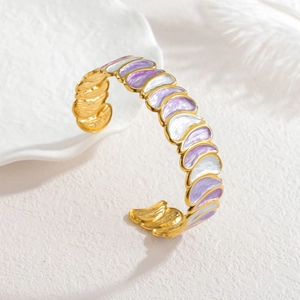 Elegant gold open bangle with purple and white teardrop enamel petals on stone background