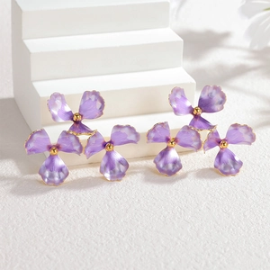 Three-layered purple floral stud earrings with golden pistils on a white display