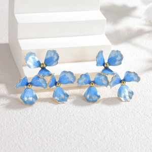 Blue and 18k gold floral earrings arranged on minimalist white geometric display