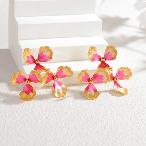 Vintage gold-trimmed pink enamel flower earrings on white stone display stand