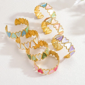Détail de joncs ouverts en acier doré 18 carats avec cœurs en émail multicolores