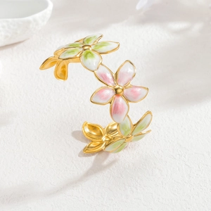 18k gold open bangle with colorful enamel floral details on white stone surface