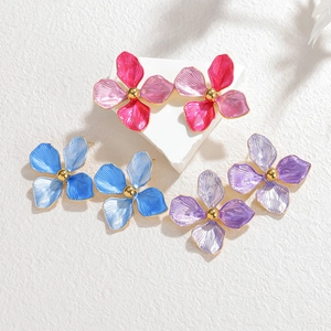 Floral stainless steel stud earrings in pink blue and purple on a white platform