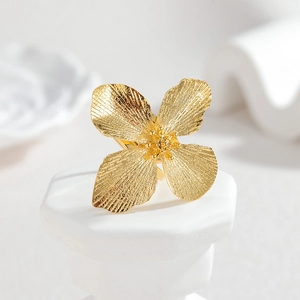 Bague ouverte fleur dorée bohème avec texture brossée sur un support d'exposition blanc