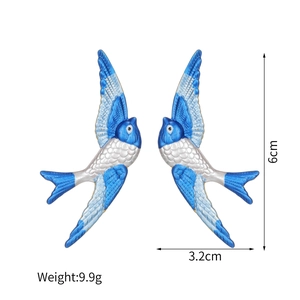 Detail view of bird wing earrings showing blue and white enamel with 6cm size marking