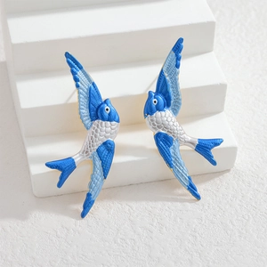 Elegant blue enamel swallow bird earrings in stainless steel on minimalist white steps