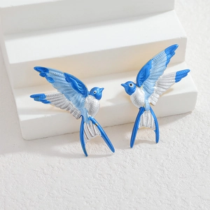 Artistic bird stud earrings in blue and white enamel with gold edges on white steps