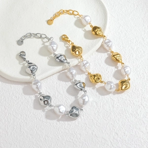 Elegant gold and silver baroque pearl bracelets on a white textured display tray