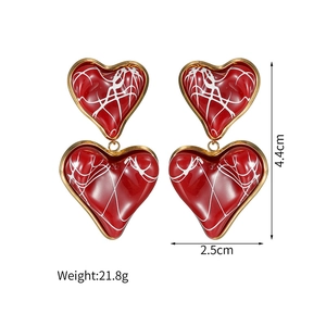 Detail view of red enamel heart earrings with gold trim and size dimensions info