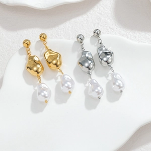 Orecchini barocchi con perle irregolari in oro e argento su un piatto di ceramica