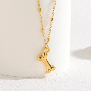 Collier en acier inoxydable plaqué or 18k avec pendentif os sur support blanc