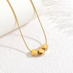 Minimalist gold snake chain necklace featuring three geometric beads on white background