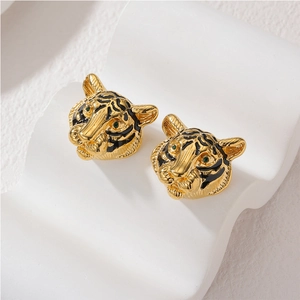 3D tiger head stud earrings in gold finish with black enamel and green gemstone eyes