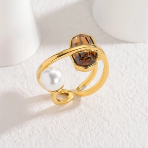 Gold geometric ring featuring a brown oval zircon and large white pearl on twin-band