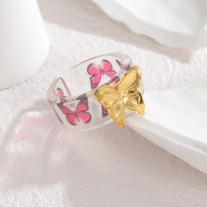 Adjustable resin butterfly ring featuring clear band with pink butterfly pattern and gold butterfly