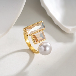 Anello aperto dorato minimalista con cristalli quadrati champagne e una perla bianca