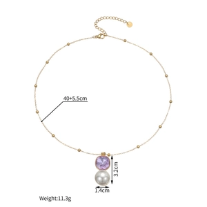 Détail d'un collier doré avec un zircon violet carré et un pendentif en perle blanche