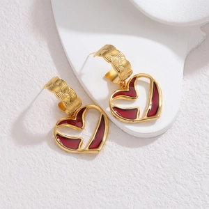 Boucles d'oreilles cœur doré avec texture tissée et émail rouge sur socle blanc