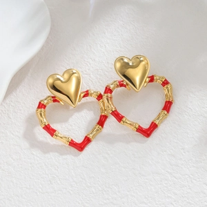 Fashion 18k gold heart earrings with red bamboo texture rings on stone background