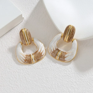 Boucles d'oreilles géométriques dorées 18K avec résine marbrée sur socle blanc