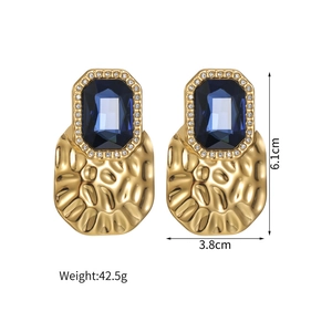 Detail view of gold earrings with large blue rectangular gems and textured metal