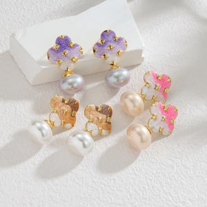 Detailed macro view of enamel clover earrings with oversized pearls in three colors