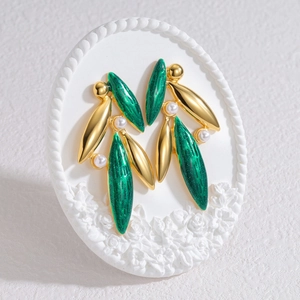 Elegant 18k gold leaf earrings with green glitter accents and pearls on a white stand
