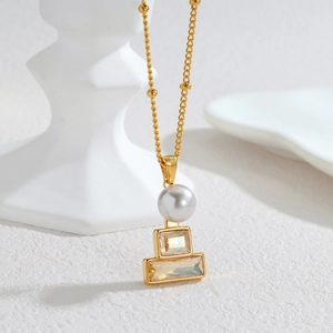 Elegant 18k gold pearl necklace with geometric champagne zircon on a white stone base