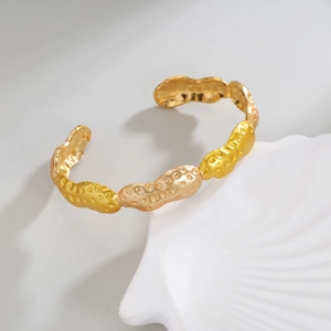 18k gold plated stainless steel peanut shape open bangle on a white shell tray