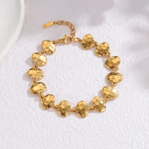 Golden geometric hammered bracelet with irregular oval links on white textured surface
