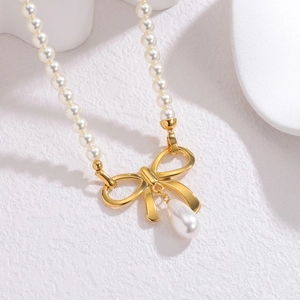 Collier de perles élégant avec pendentif nœud doré et perle goutte sur fond blanc