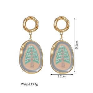 Detail of 18k gold plated oval earrings with green tree motif and hook closure