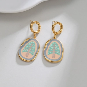 Elegant 18k gold oval earrings with green tree enamel drop on textured white surface