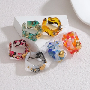 Set of 6 colorful resin open rings with gold heart accents on white marble pedestals